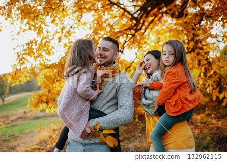 A portrait of young family with two small children in autumn nature at sunset. A portrait of young family with two small children in autumn nature at sunset. 132962115