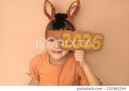 A person dressed up as a symbol of the new year 2026 with a brown horse make-up and ears on her head. Waiting for the holidays 132962244