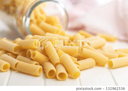 Uncooked rigatoni pasta on white table. 132962536