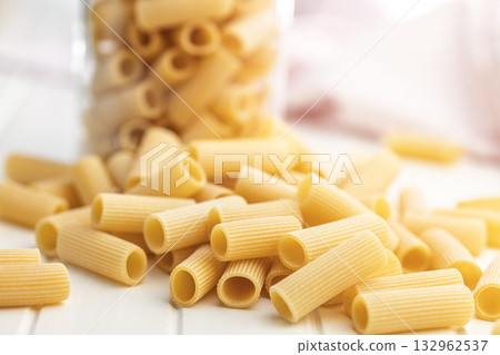 Uncooked rigatoni pasta on white table. Uncooked rigatoni pasta on white table. 132962537