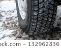 Car wheel with snow tire on the winter gravel road Car wheel with snow tire on the winter gravel road 132962836