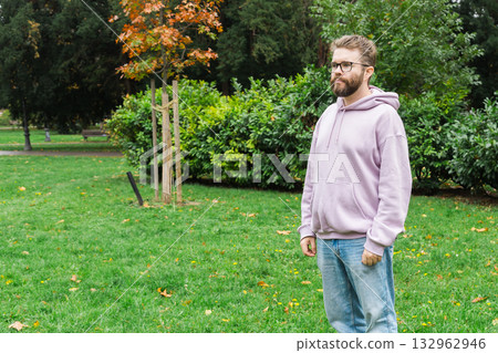 Man standing near autumn tree in park. Copy space and empty place for advertising. Simplicity, calm reflection and urban leisure. 132962946