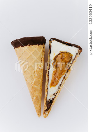 Sliced vanilla ice cream cone with caramel filling and chocolate coating on white background 132963419