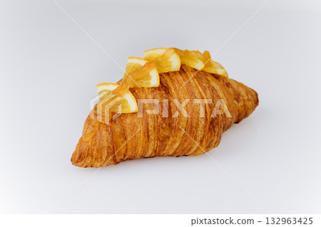 Golden croissant topped with candied orange slices on white background, gourmet bakery pastry Golden croissant topped with candied orange slices on white background, gourmet bakery pastry 132963425