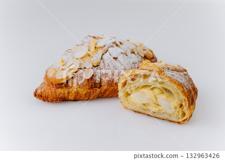 Almond croissant cut in half with creamy filling and powdered sugar on white background Almond croissant cut in half with creamy filling and powdered sugar on white background 132963426