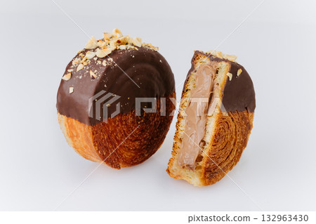 Chocolate round croissant with hazelnuts and creamy filling on white background 132963430