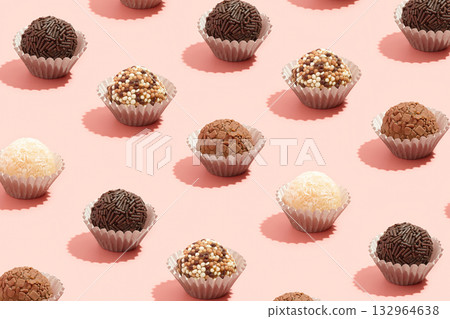 Typical Brazilian sweet brigadeiro. Assorted flavors of candies in a line on a pink background 132964638