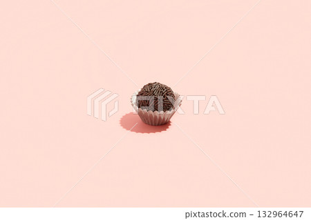 Typical Brazilian sweet brigadeiro. One candy with chocolate sprinkles on a pink background Typical Brazilian sweet brigadeiro. One candy with chocolate sprinkles on a pink background 132964647