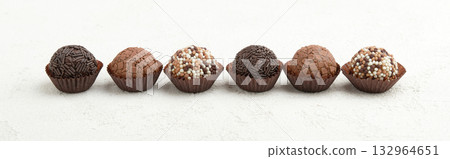 Typical Brazilian sweet brigadeiro. Assorted flavors of candies in a line on a white table 132964651