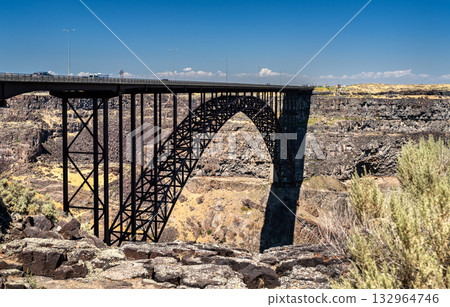 A view of the Perrine Bridge arch in Twin Falls, Idaho. The steel structure spans the deep basalt cliffs of the Snake River Canyon under a clear blue sky. Represents engineering and infrastructure A view of the Perrine Bridge arch in Twin Falls, Idaho. The steel structure spans the deep basalt cliffs of the Snake River Canyon under a clear blue sky. Represents engineering and infrastructure 132964746