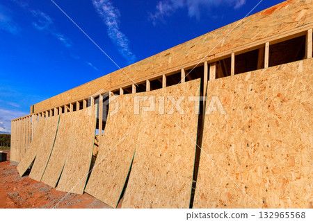 Workers are preparing wooden structure of building with sheets of plywood board placed on exterior facing Workers are preparing wooden structure of building with sheets of plywood board placed on exterior facing 132965568