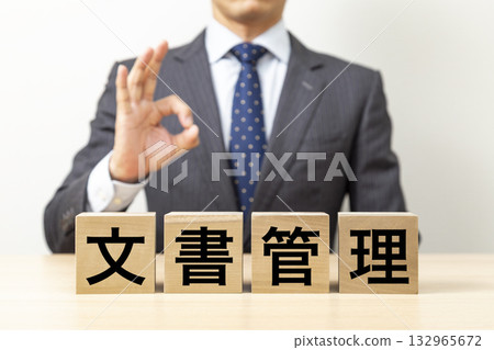 一位商人擺出「OK」的手勢，旁邊立著一塊寫著「文件管理」的積木。 132965672