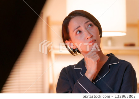 A woman in pajamas with a thinking expression 132965802