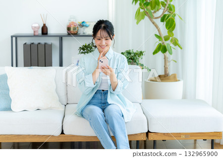 A young woman operating a smartphone in a room 132965900