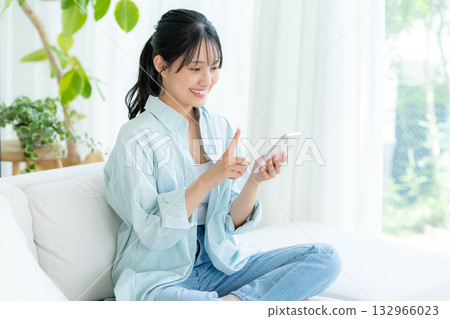 A young woman operating a smartphone in a room A young woman operating a smartphone in a room 132966023