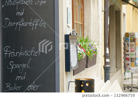 A street scene with a board displaying a restaurant menu written in German A street scene with a board displaying a restaurant menu written in German 132966759