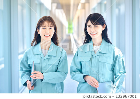 Two smiling female staff members in work clothes standing in the hallway 132967001
