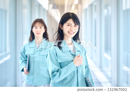 Two women in work clothes walking down the hallway with smiles 132967002