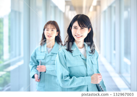 Two women in work clothes walking down the hallway with smiles 132967003
