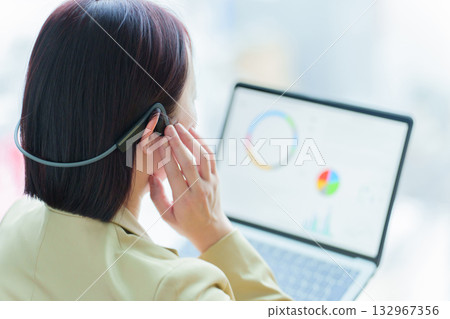 A businesswoman working at her desk wearing bone conduction earphones A businesswoman working at her desk wearing bone conduction earphones 132967356