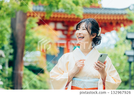 A woman in a kimono praying with a smartphone A woman in a kimono praying with a smartphone 132967926