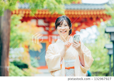 一位身穿和服的女子正在用智慧型手機祈禱 132967927