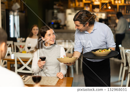 Male waiter brings dishes that the couple ordered 132968031