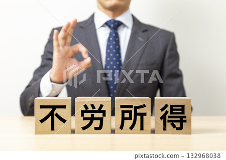 一名商人擺出「OK」的姿勢,旁邊立著一塊寫著「非勞動所得」的牌子。 一名商人擺出「OK」的姿勢,旁邊立著一塊寫著「非勞動所得」的牌子。 132968038