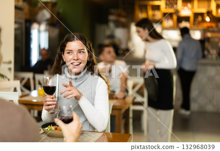 Girl in cafe sits opposite male companion, has nice conversation 132968039