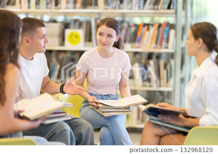 Students reading books while sitting in chairs Students reading books while sitting in chairs 132968120