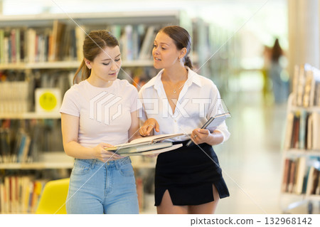 Two students talking in the library 132968142