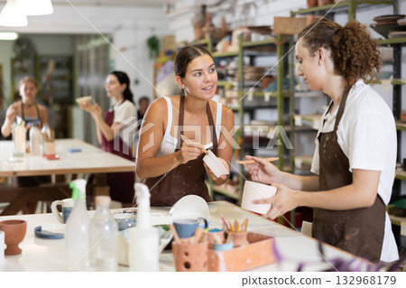 Girl and man processing clay bowls in carpentry workshop 132968179