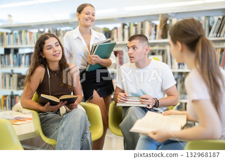 Group of students reading and discussing books in library 132968187