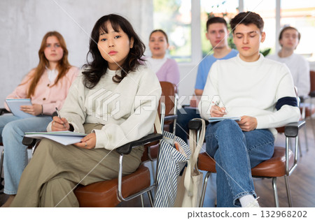 Asian girl student listening to lecture and taking notes Asian girl student listening to lecture and taking notes 132968202