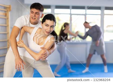 Young woman and guy training self-defense techniques Young woman and guy training self-defense techniques 132968204