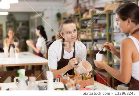 Young girl and guy painting with brush on handmade ceramic bowl Young girl and guy painting with brush on handmade ceramic bowl 132968243