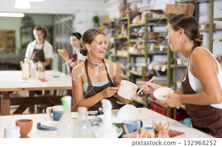 Girls processing clay bowls in carpentry workshop 132968252
