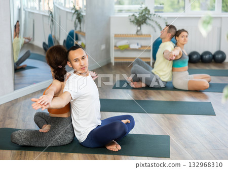 Men and women maintaining healthy lifestyle practicing partner yoga at group lesson 132968310