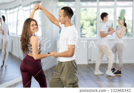 Young girl with multinational group of active people training dancing couple active swing in studio Young girl with multinational group of active people training dancing couple active swing in studio 132968342
