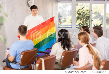 Young male professor showing rainbow flag to group of students Young male professor showing rainbow flag to group of students 132968353