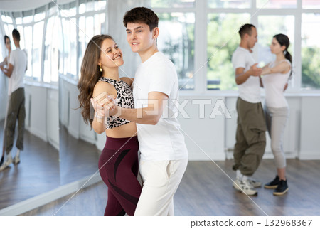 Young couple dancing playful bachata during group class Young couple dancing playful bachata during group class 132968367