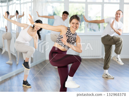 Smiling girl energizing group during dance fitness class 132968378