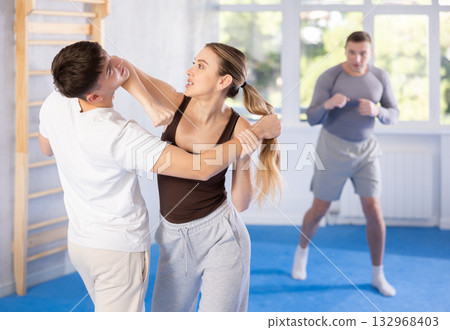 Young girl practicing self-defense techniques in pairs with guy Young girl practicing self-defense techniques in pairs with guy 132968403