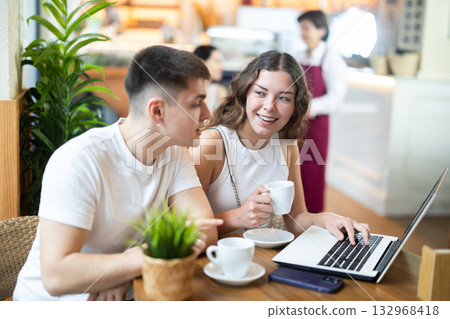 Girl and guy freelancers in cafe with laptop drinking coffee 132968418