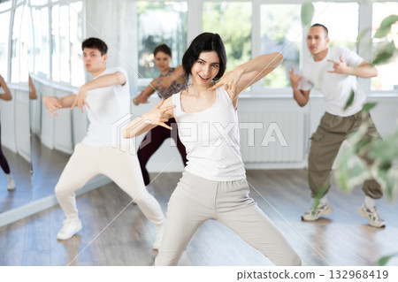 Girl enjoys active dancing, learns new movements, moves synchronously with participants of lesson 132968419