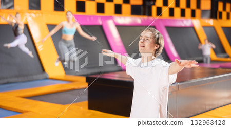 Young guy trains jumping in trampoline center 132968428