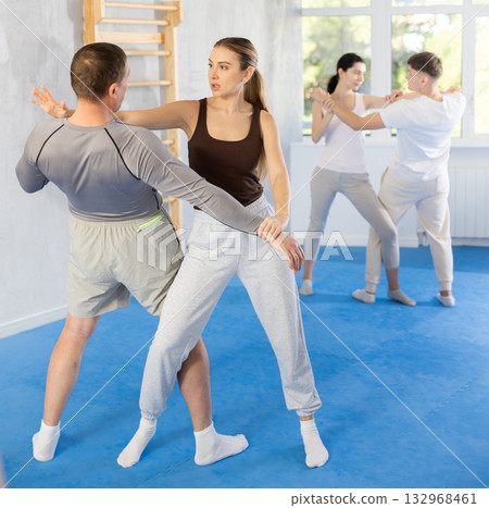 Woman practices blows to the head of a male attacker during self defense training 132968461