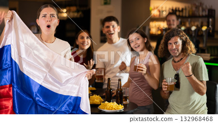 Football fans gesturing emotionally after goal scored by favorite team while watching championship match on TV in sports bar with Russian flag Football fans gesturing emotionally after goal scored by favorite team while watching championship match on TV in sports bar with Russian flag 132968468