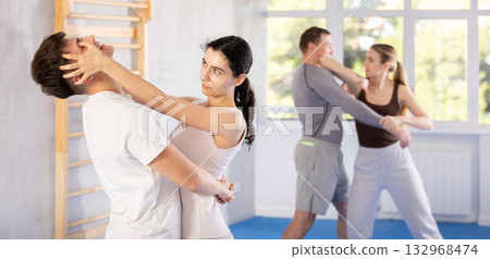 Young girl practicing self-defense techniques in pairs with guy Young girl practicing self-defense techniques in pairs with guy 132968474