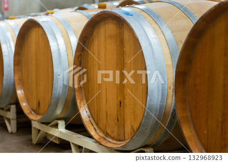 酒窖裡擺放著一排排的葡萄酒桶——酒莊儲藏室一覽。 酒窖裡擺放著一排排的葡萄酒桶——酒莊儲藏室一覽。 132968923